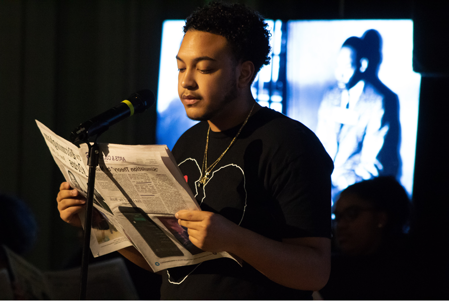 A student standing in front of a microphone during a Black History Month performance.